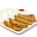 Neehee's Aloo Paratha meal platter, served with a side of curd and pickle.