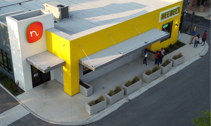 Aerial view of the Neehee's Indian Vegetarian Cuisine restaurant building with yellow facade and outdoor patio seating area.